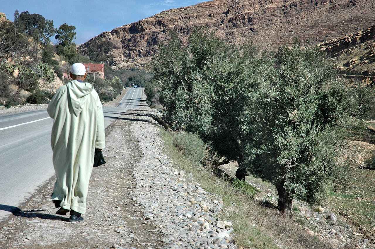 an elderly man wearing traditional Jalaba walking on the side of the street in Agadir