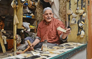 an elderly man working making head brushes in Fez